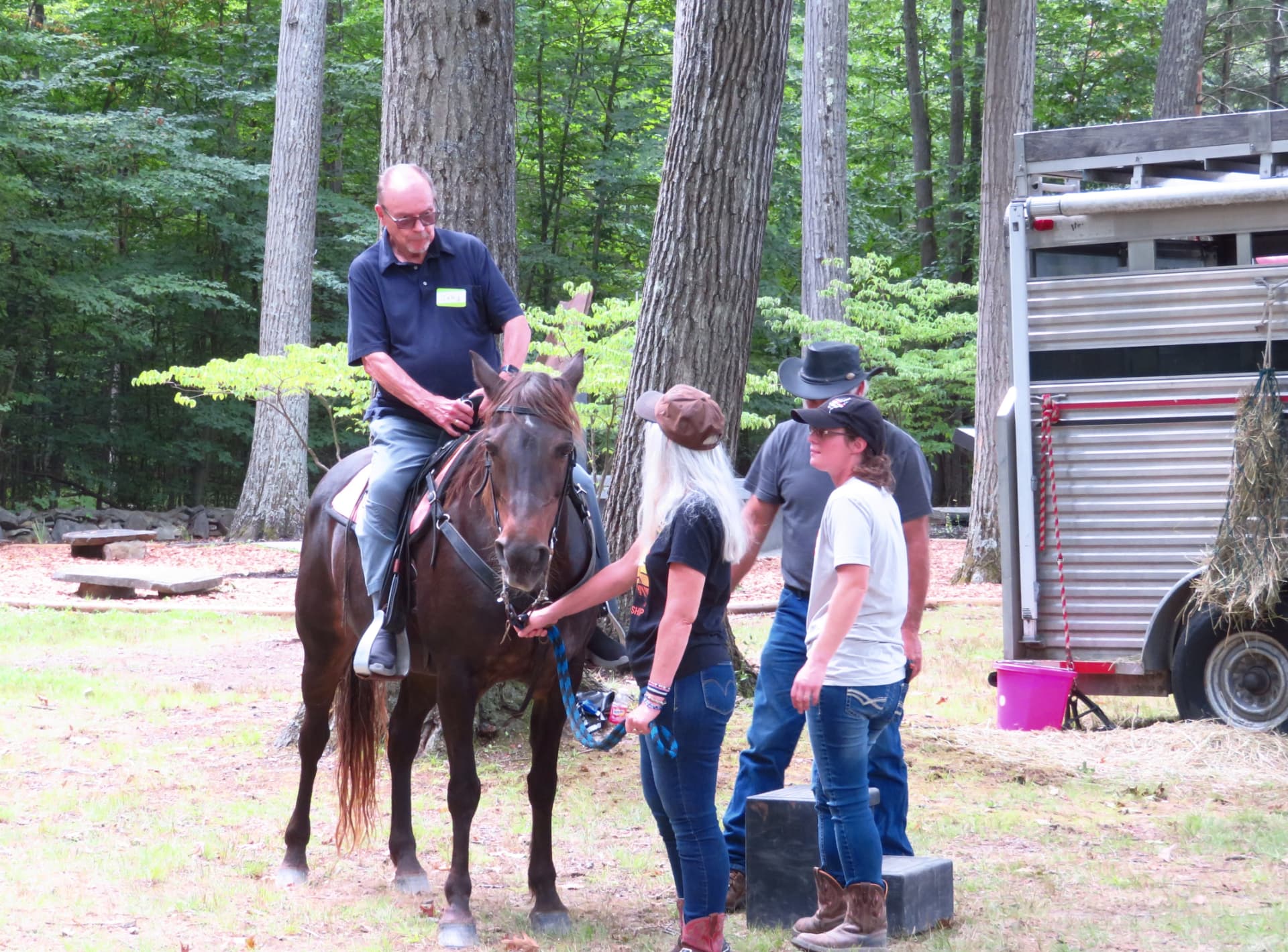 A member riding horseback with helpers steadying the horse