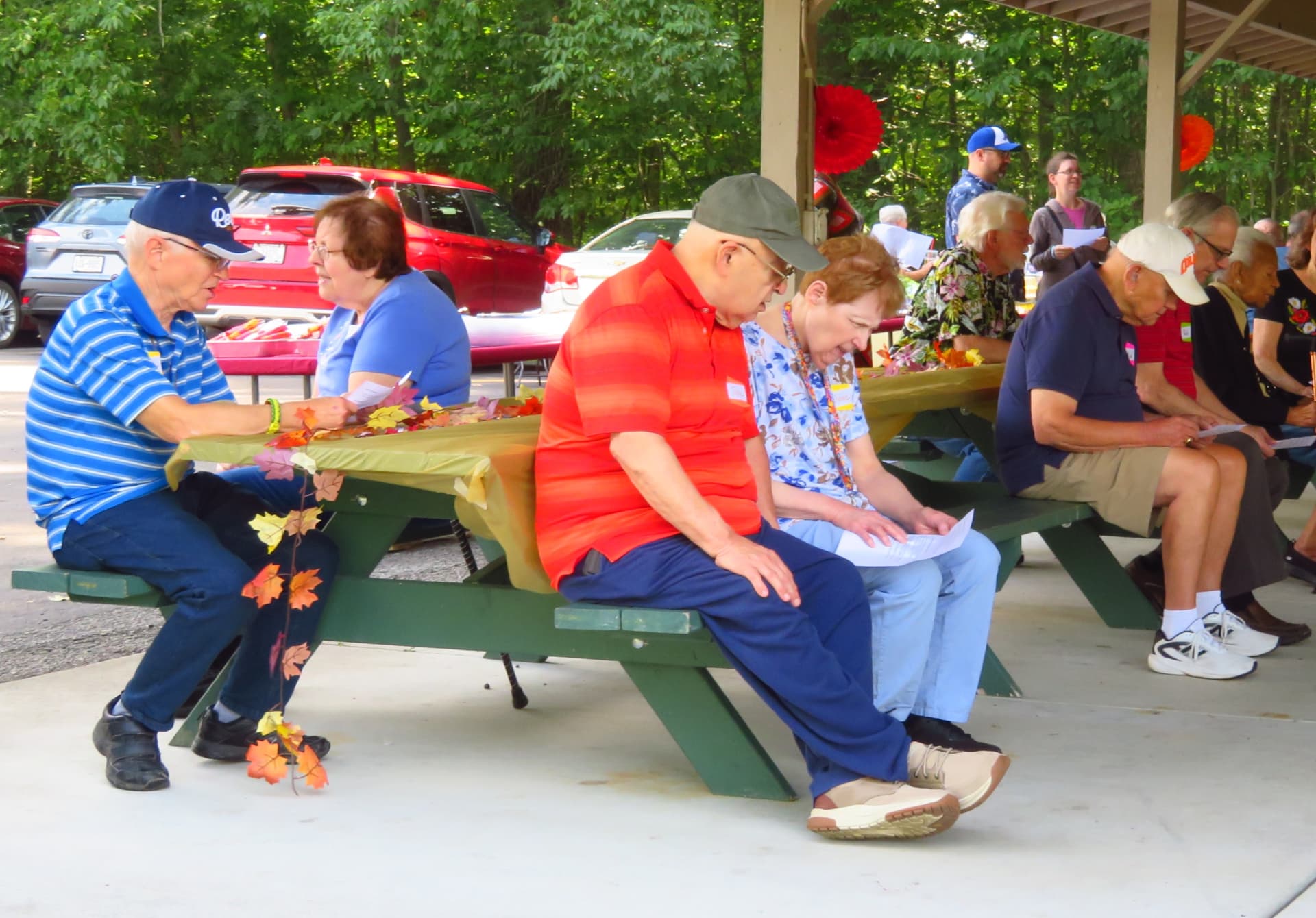 Members seated at decorated picnic tables following along with song sheets