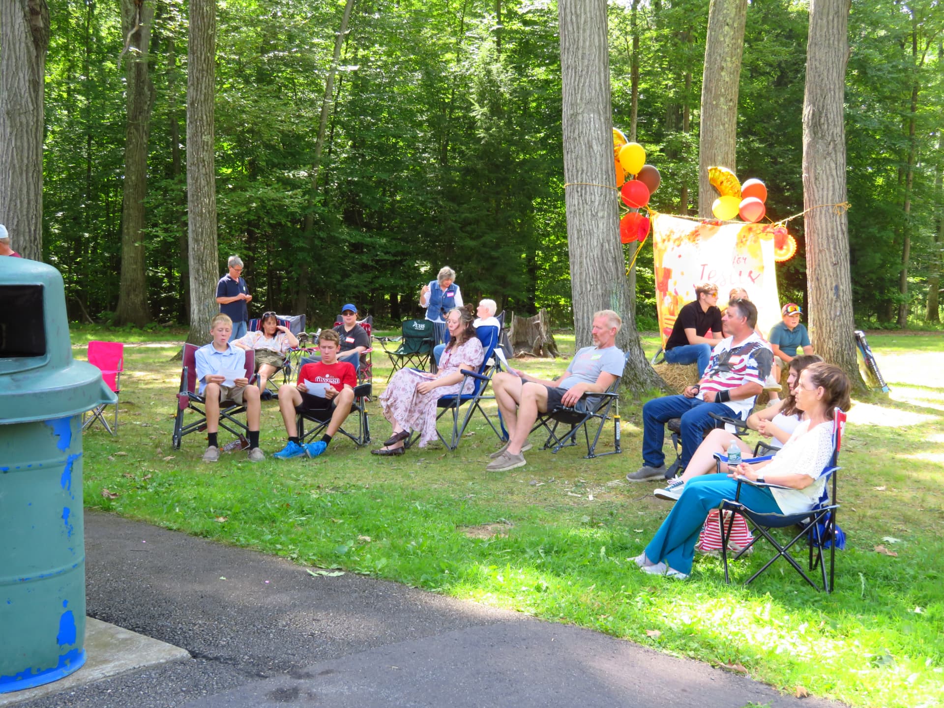 Attendees seated in lawn chairs on the grass during the program