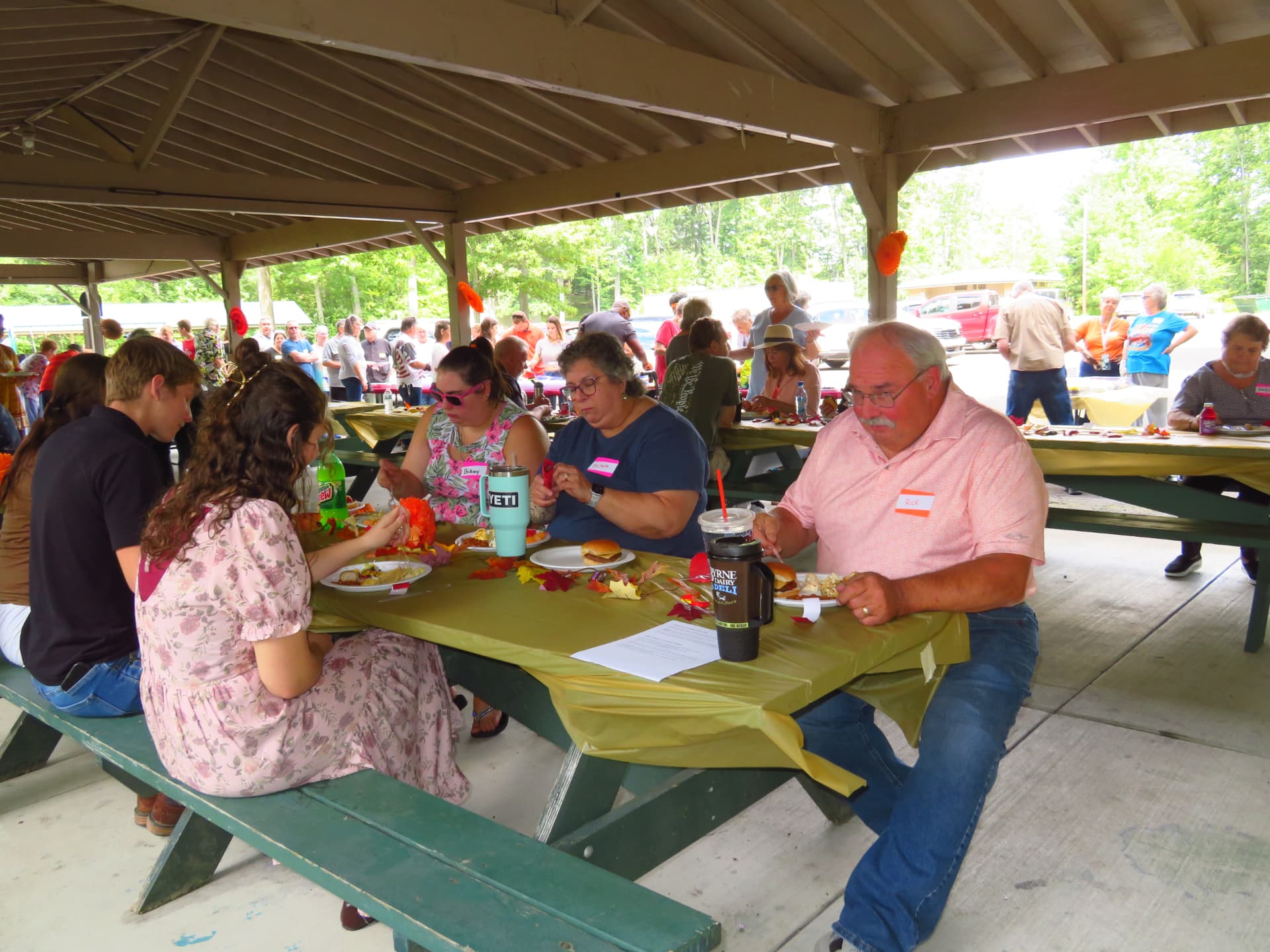 Members eating together under the pavilion as the crowd gathers