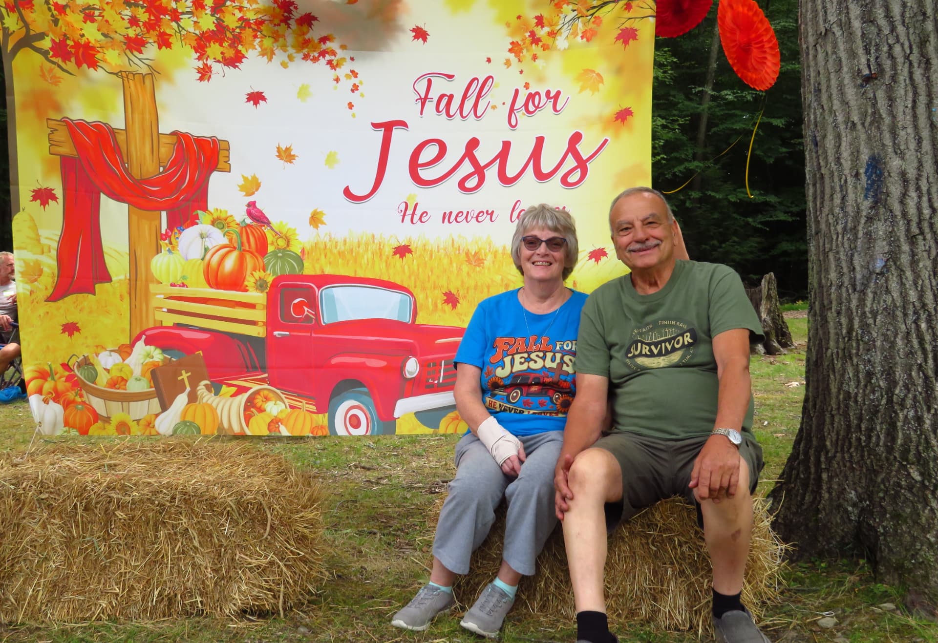 Two members in Fall for Jesus shirts seated at the photo backdrop