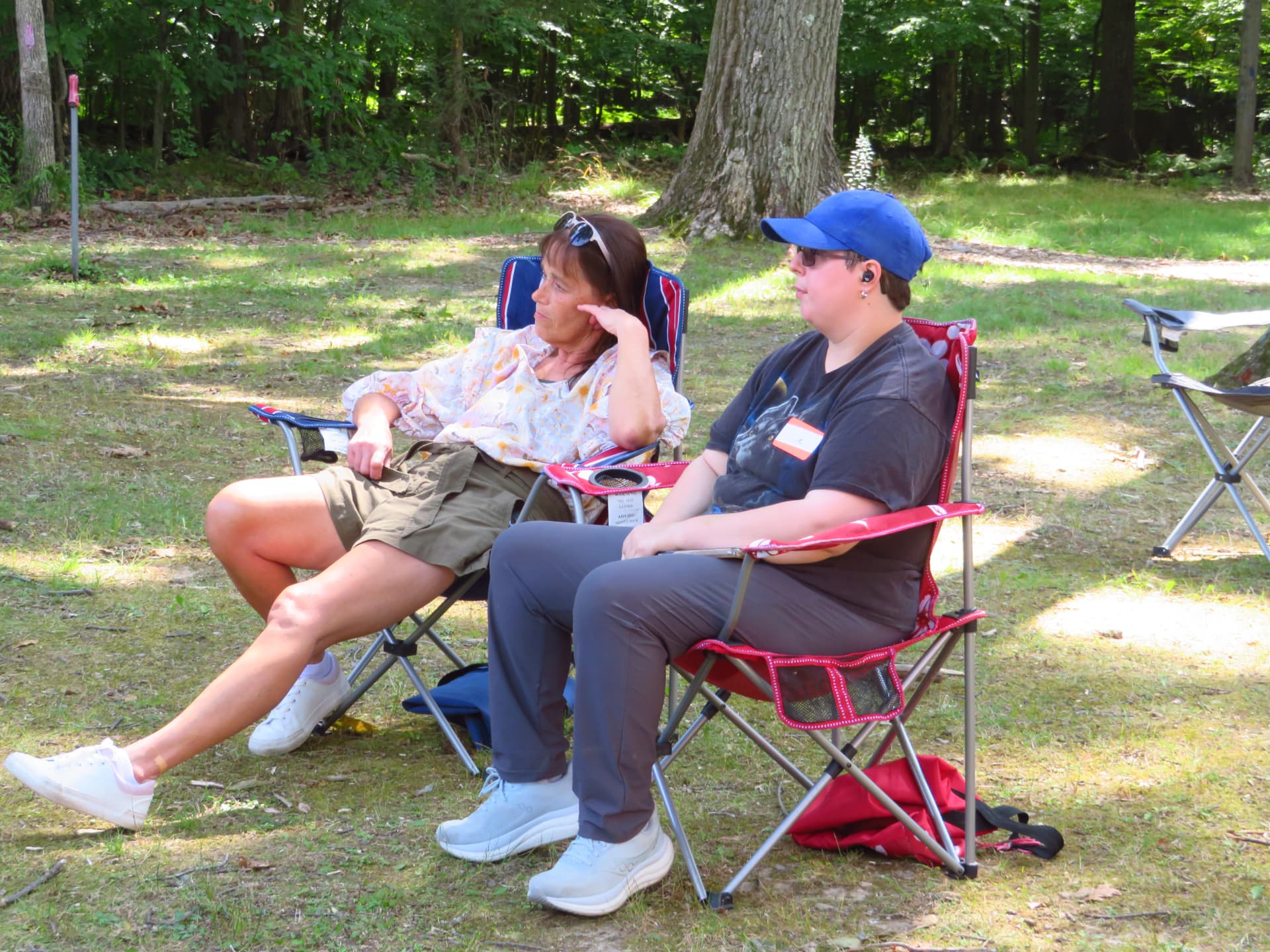 Two attendees relaxing in lawn chairs in the shade