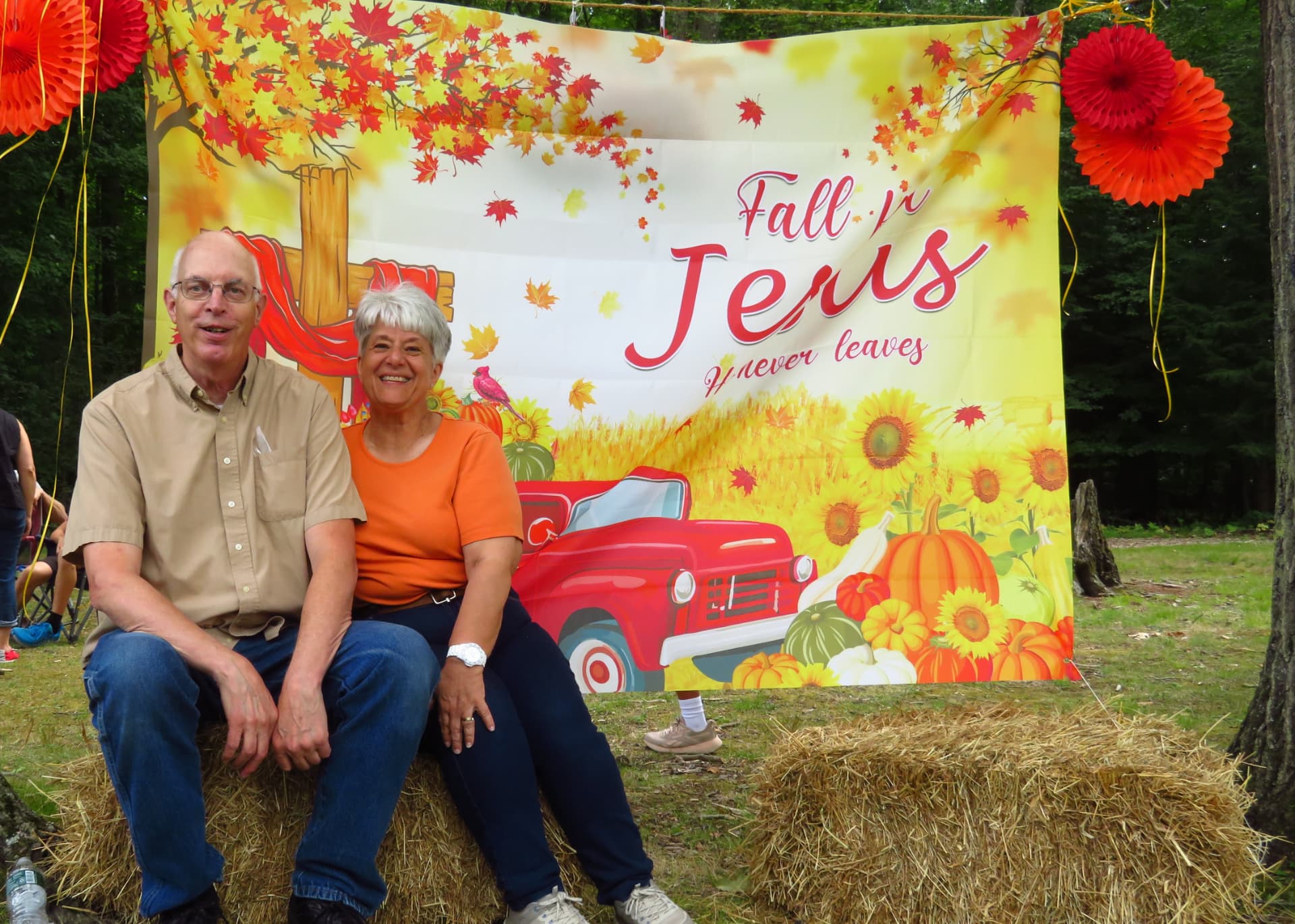 A couple laughing together in front of the fall banner