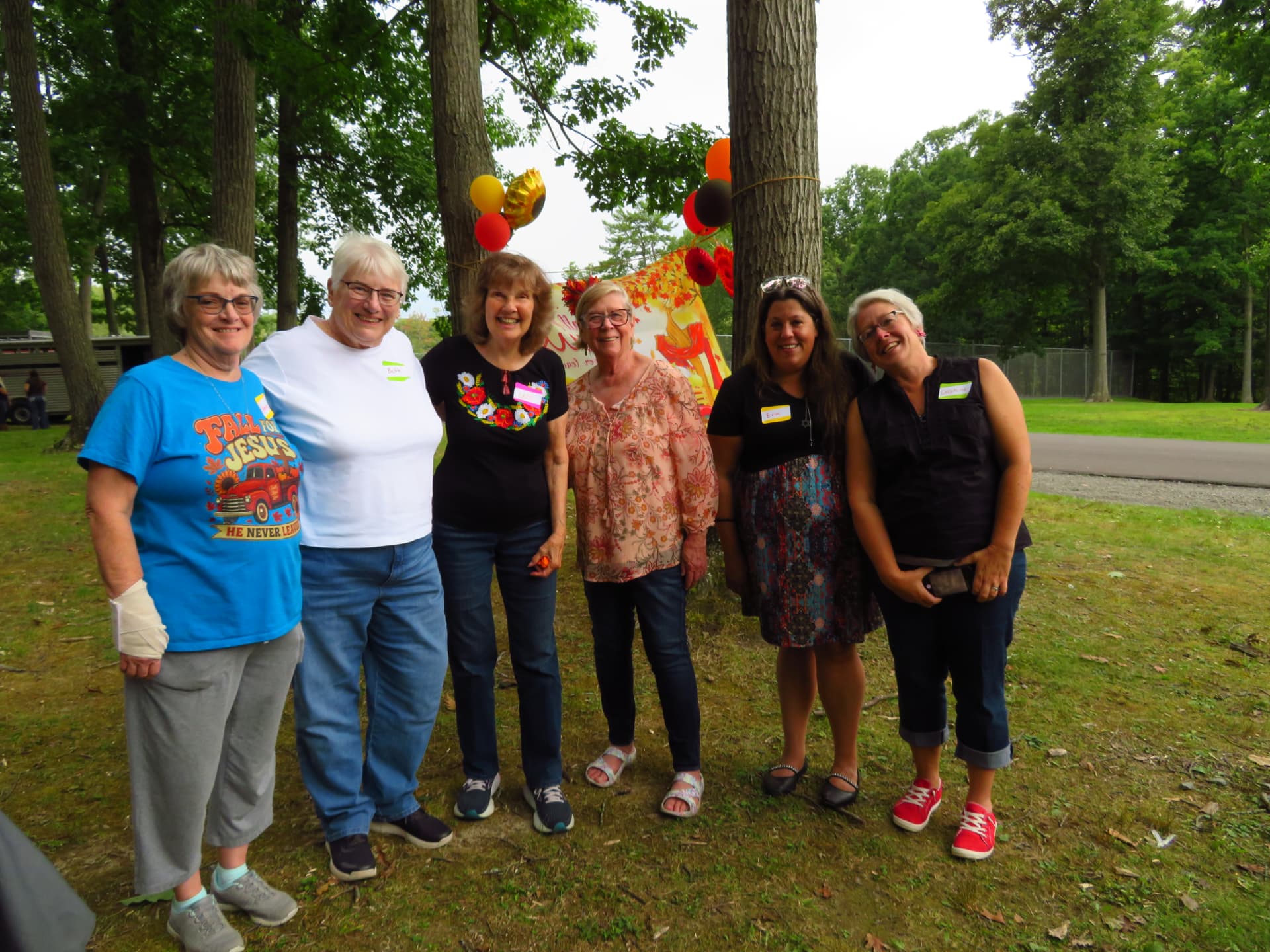 Ladies of the church posing together near the fall banner