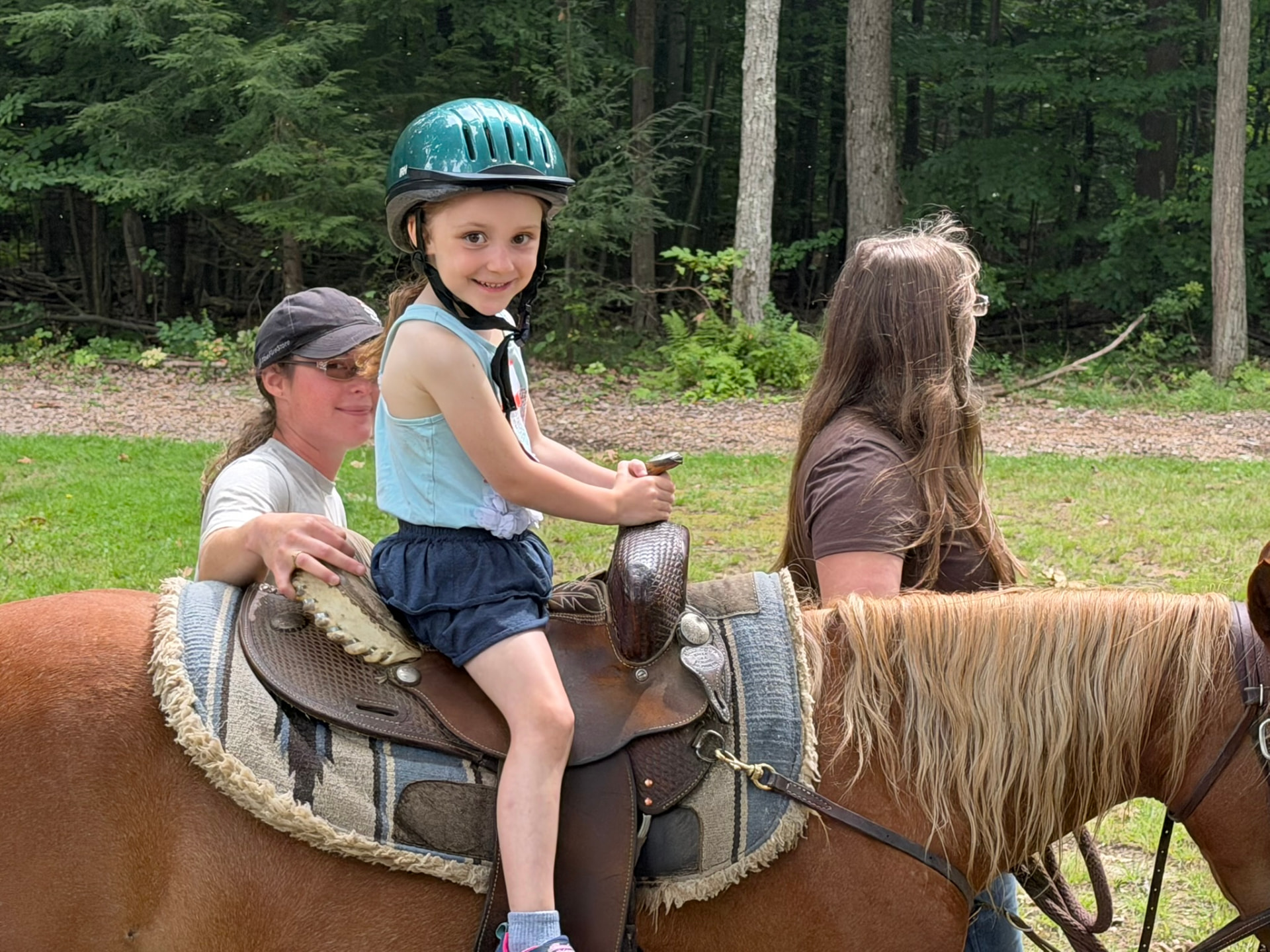 A young girl enjoying a pony ride with helpers alongside