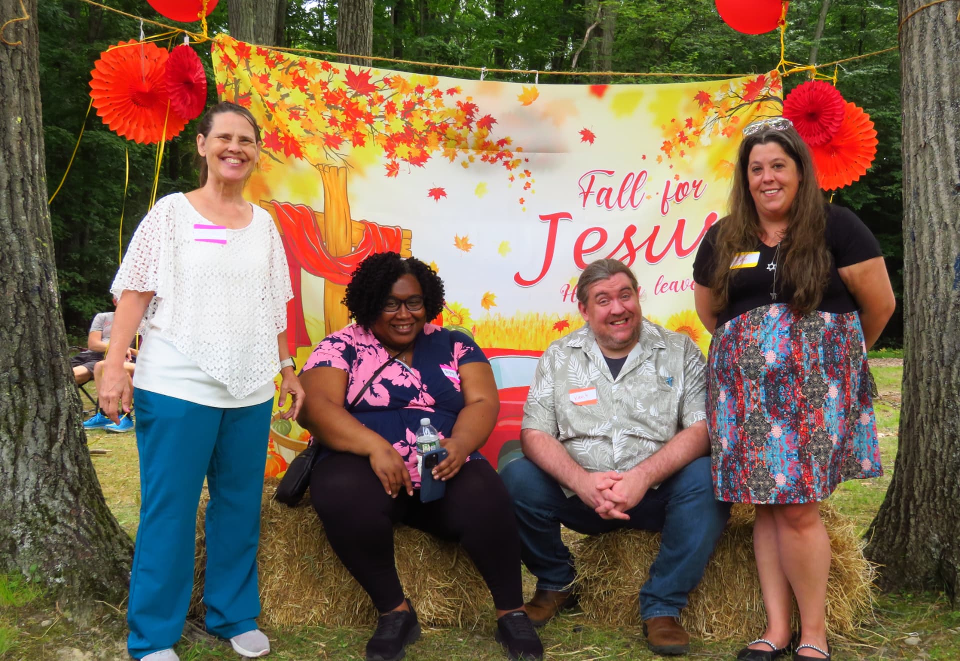 A group of four friends posing at the Fall for Jesus backdrop