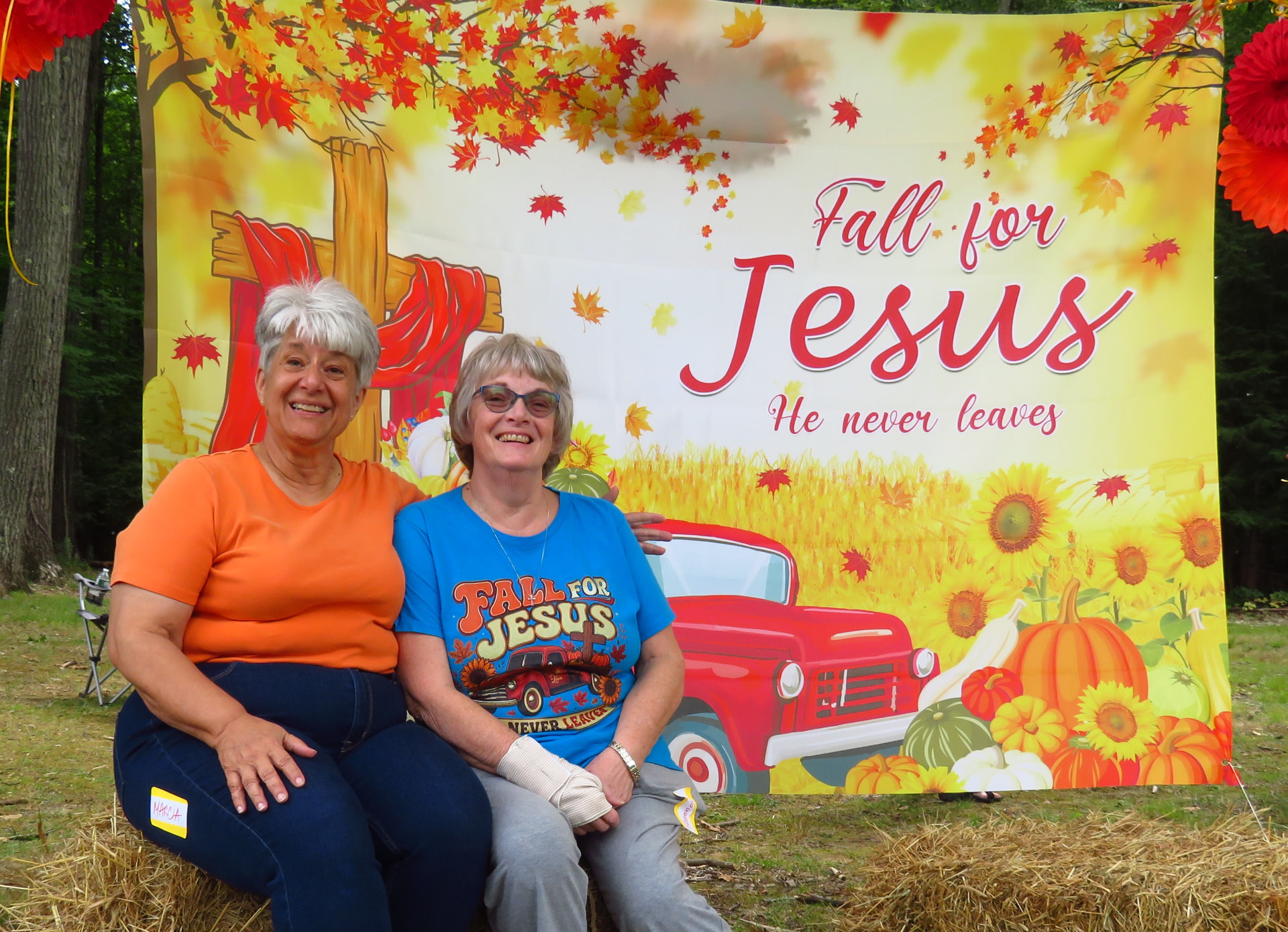Two members posing in front of the Fall for Jesus banner