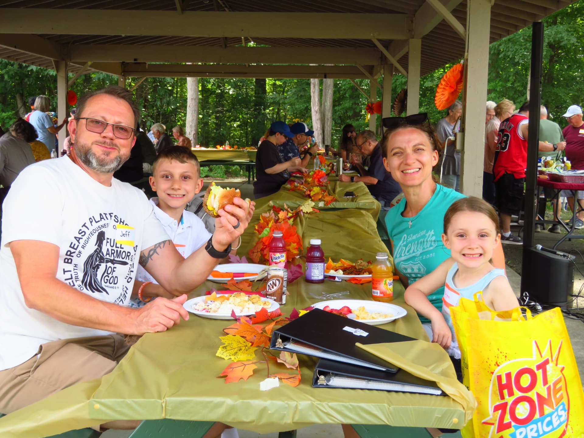 A family smiling together over burgers at the picnic